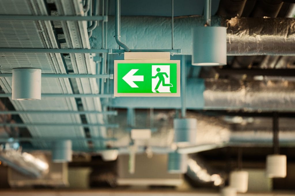 Illuminated evacuation exit sign mounted under a ceiling